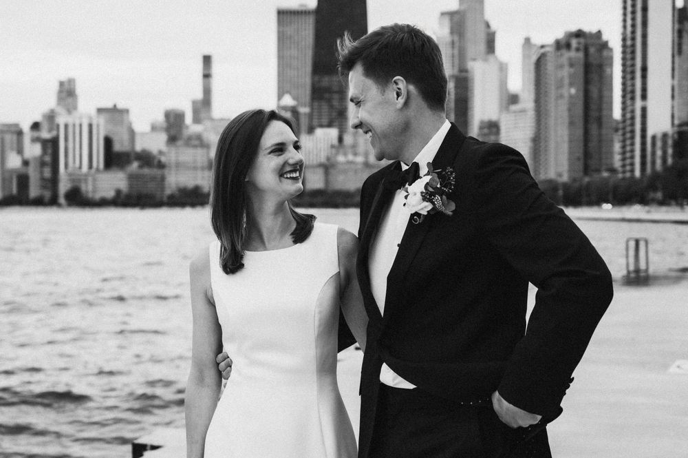 Classic black and white portrait of newlyweds along Chicago's waterfront with city skyline.