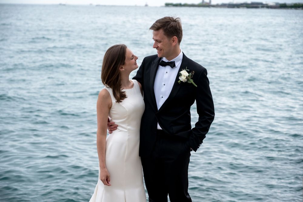 Elegant wedding couple shares intimate moment by Lake Michigan with Chicago skyline backdrop.