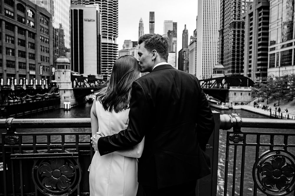 Black and white romantic moment between newlyweds on Chicago River bridge with urban backdrop.