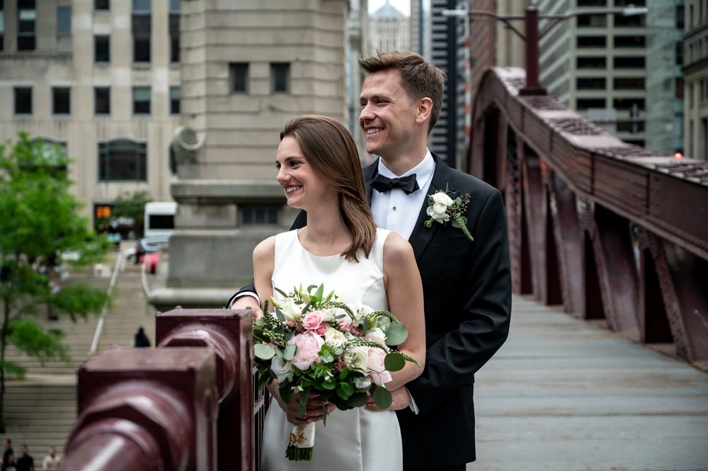Candid wedding moment on vintage Chicago bridge with bridal bouquet and city architecture.