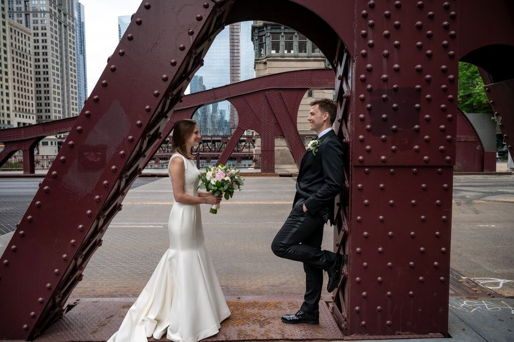 Artistic wedding photo framed within red steel bridge architecture in downtown Chicago.
