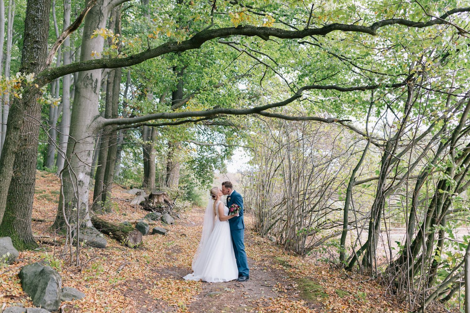 Hochzeitsfotografie - Brautpaar im Wald im Herbst weißes Kleid mit Schleier
