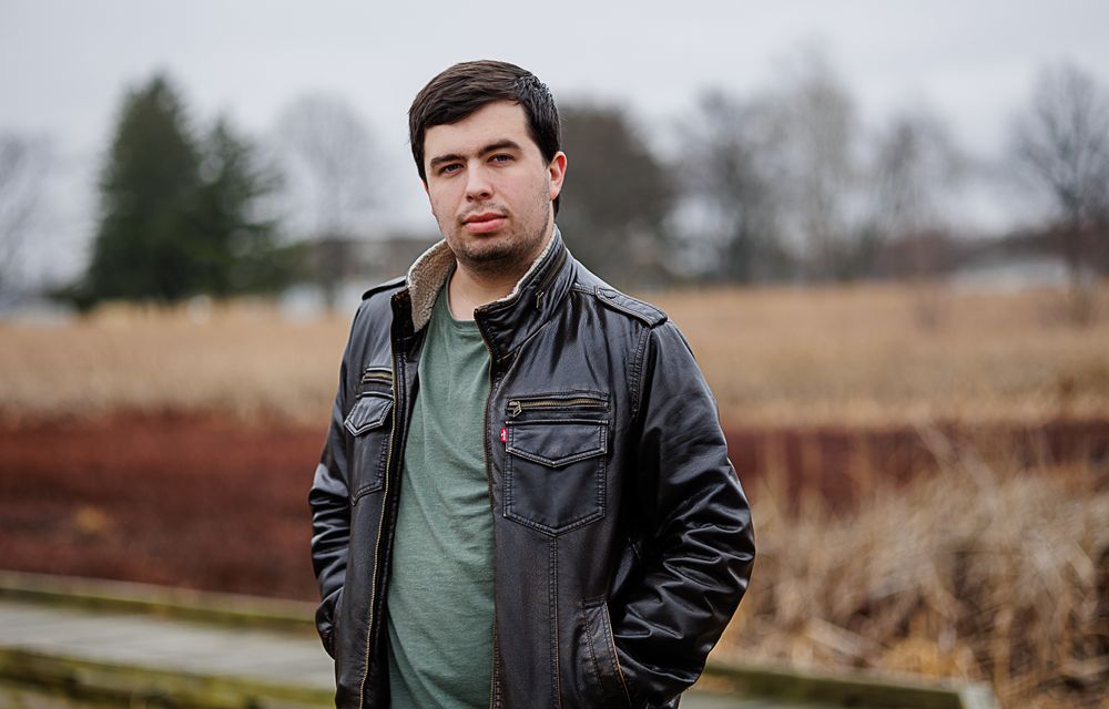 Person in a black leather jacket and green shirt walking through a winter landscape at Beckenholdt Park,