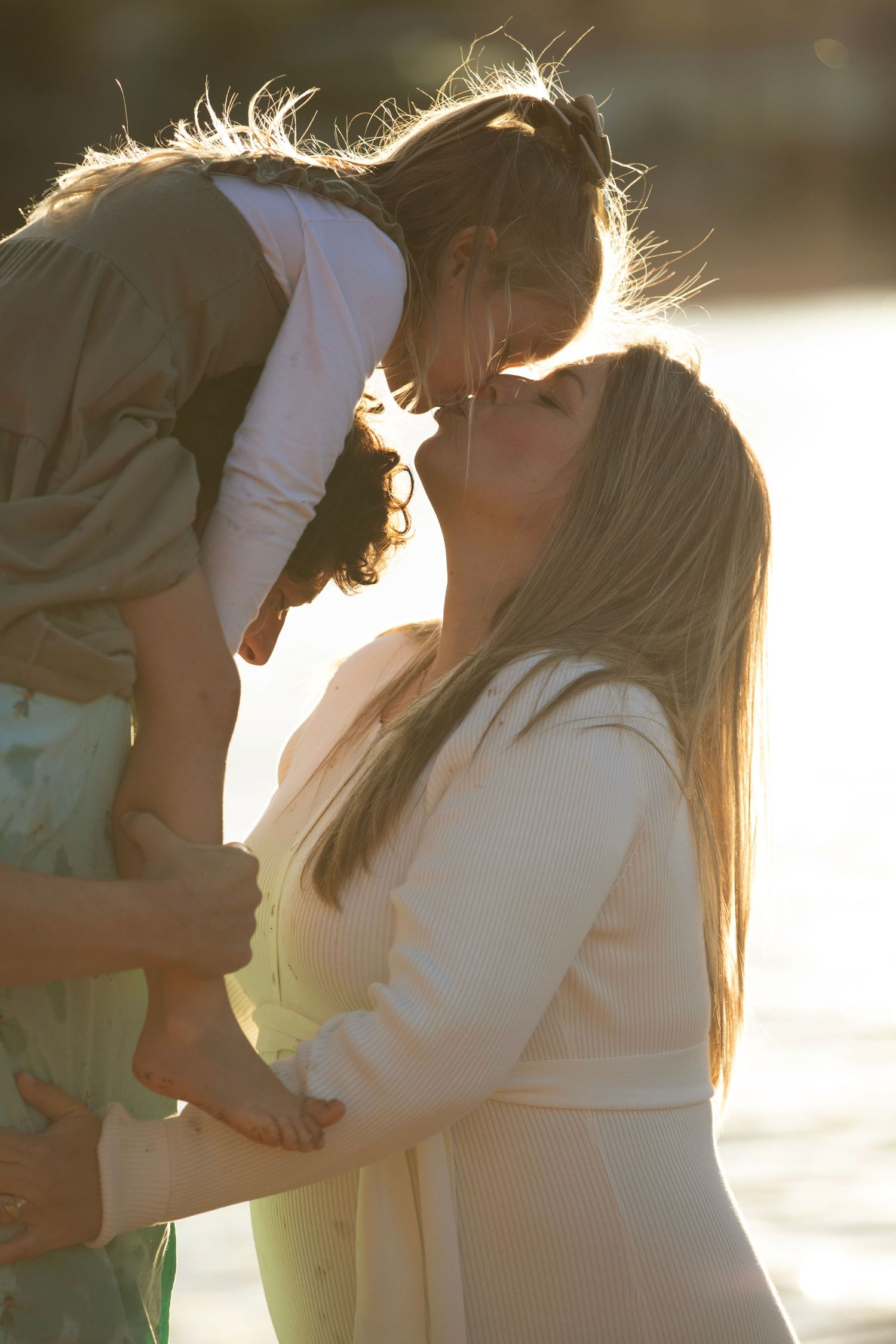 Romantic silhouette of a couple sharing an intimate moment in golden sunlight at sunset.