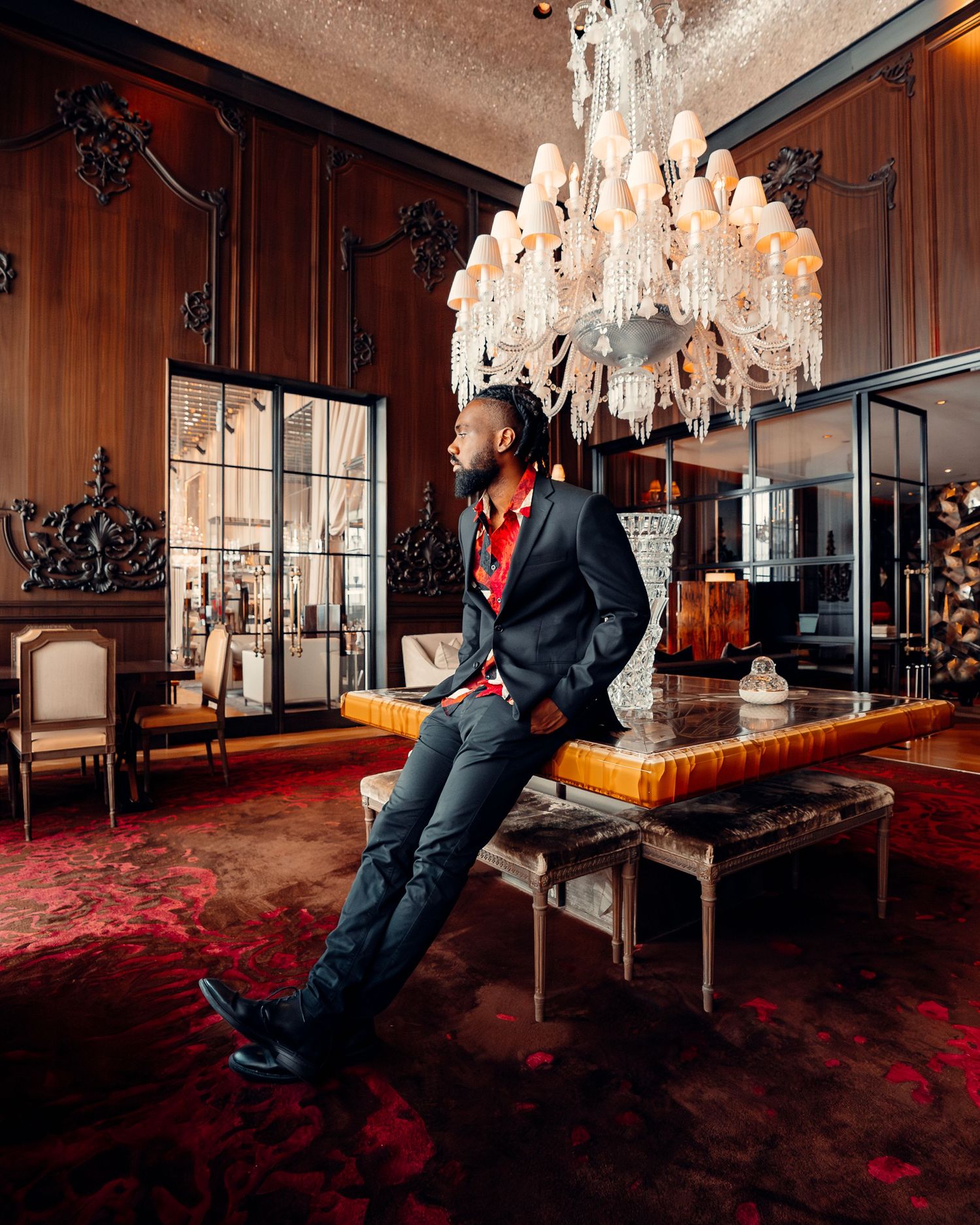Dramatic sequence in luxurious room with crystal chandeliers and red carpet.