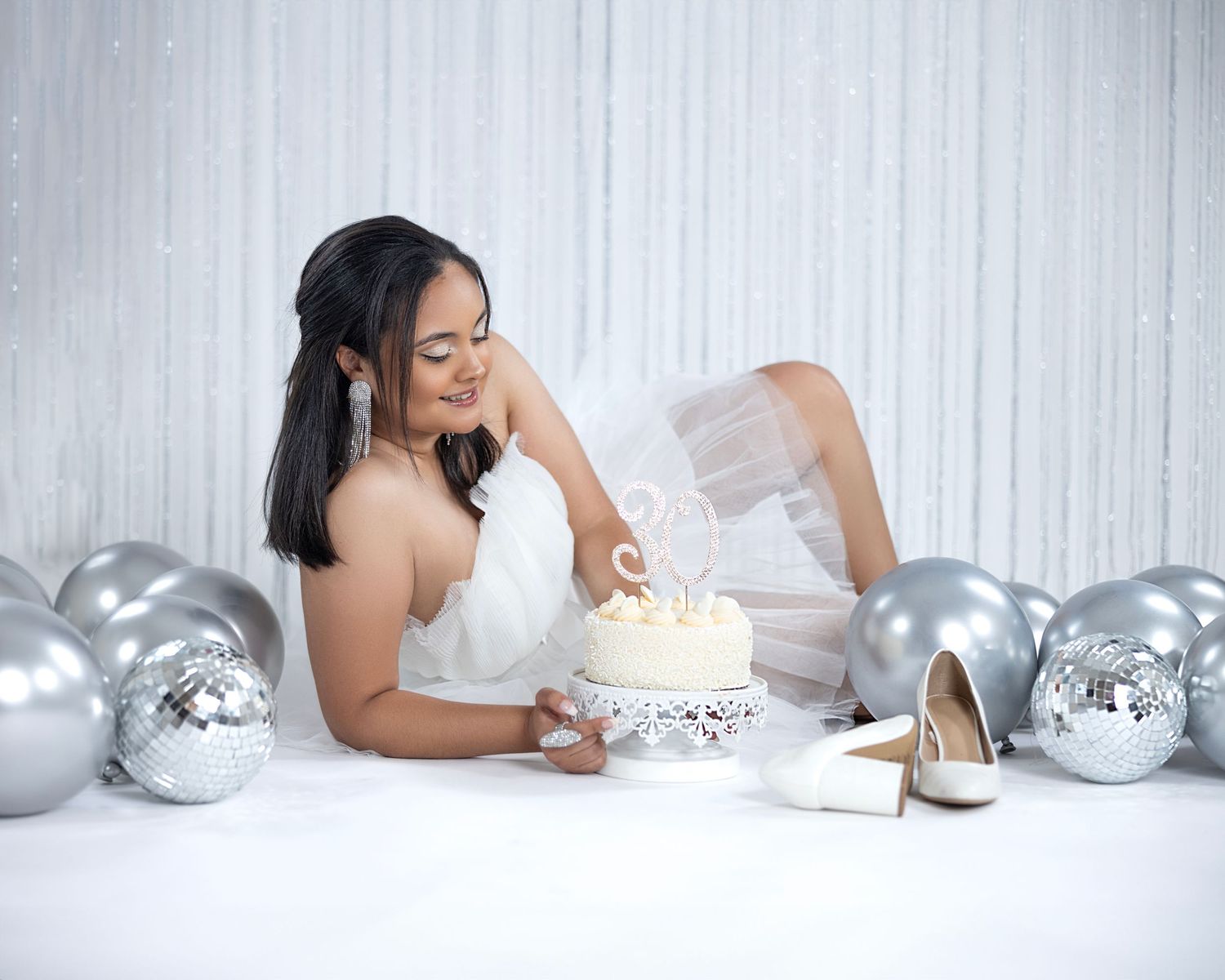 Birthday portrait with elegant cake and silver balloon decorations.
