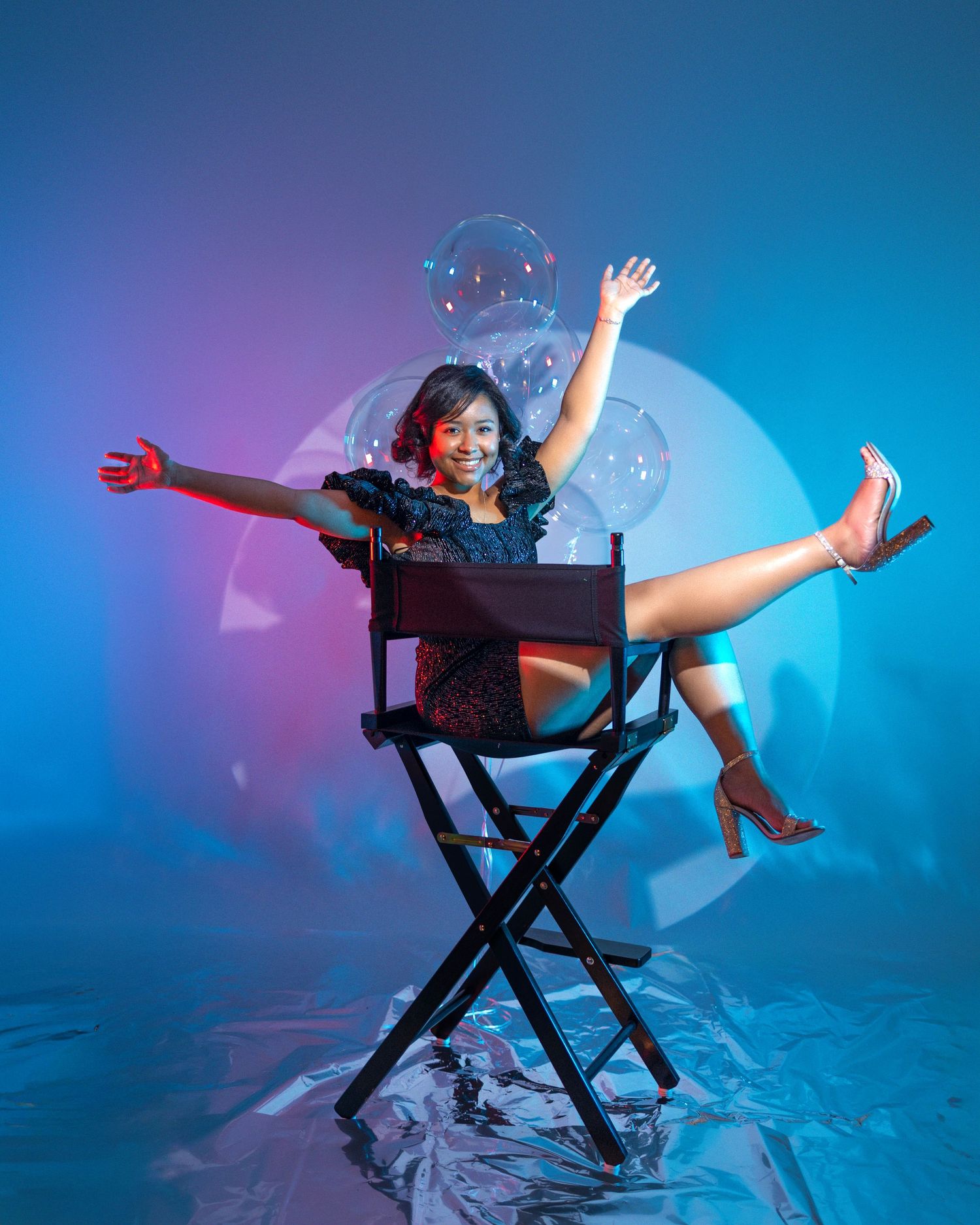 Dynamic birthday photoshoot in director's chair with blue and purple lighting.