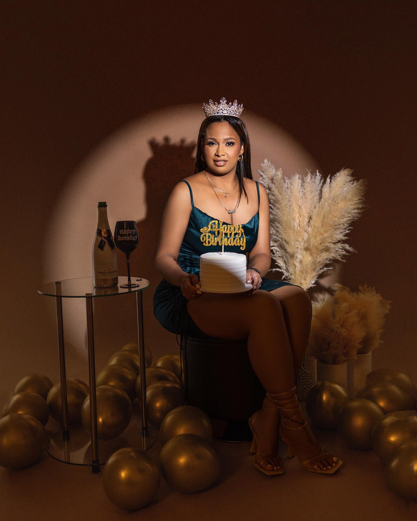 Birthday portrait with crown, gold balloons, and wine glass styling.