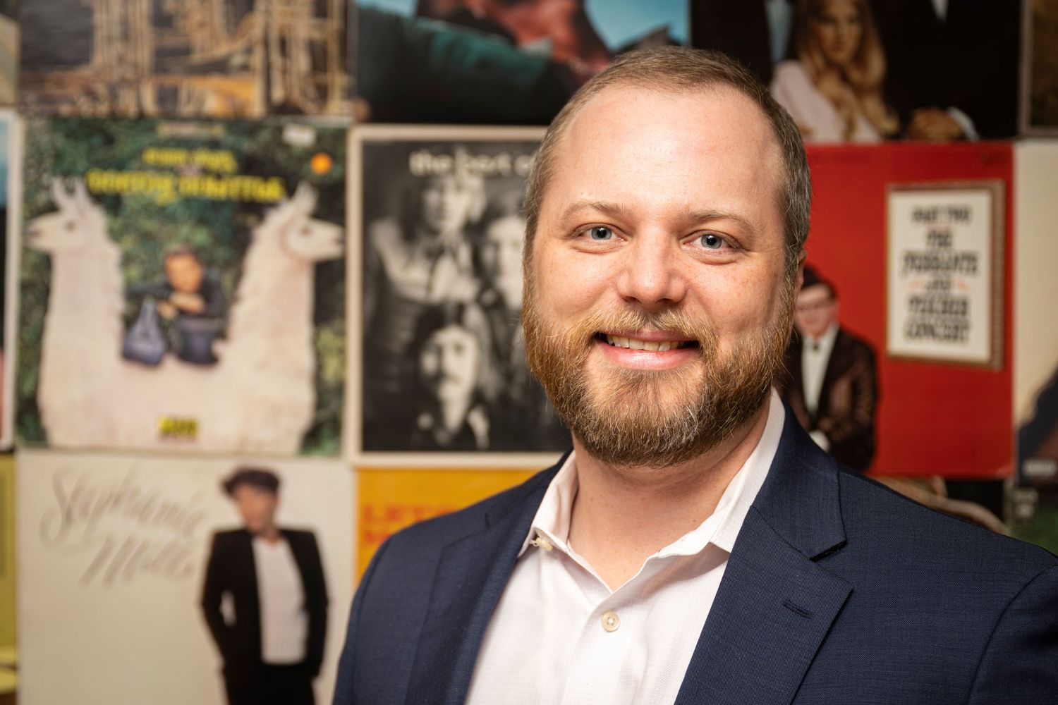 Professional portrait against wall decorated with vintage posters and artwork. Scotch Plains Photographer, portrait photography.