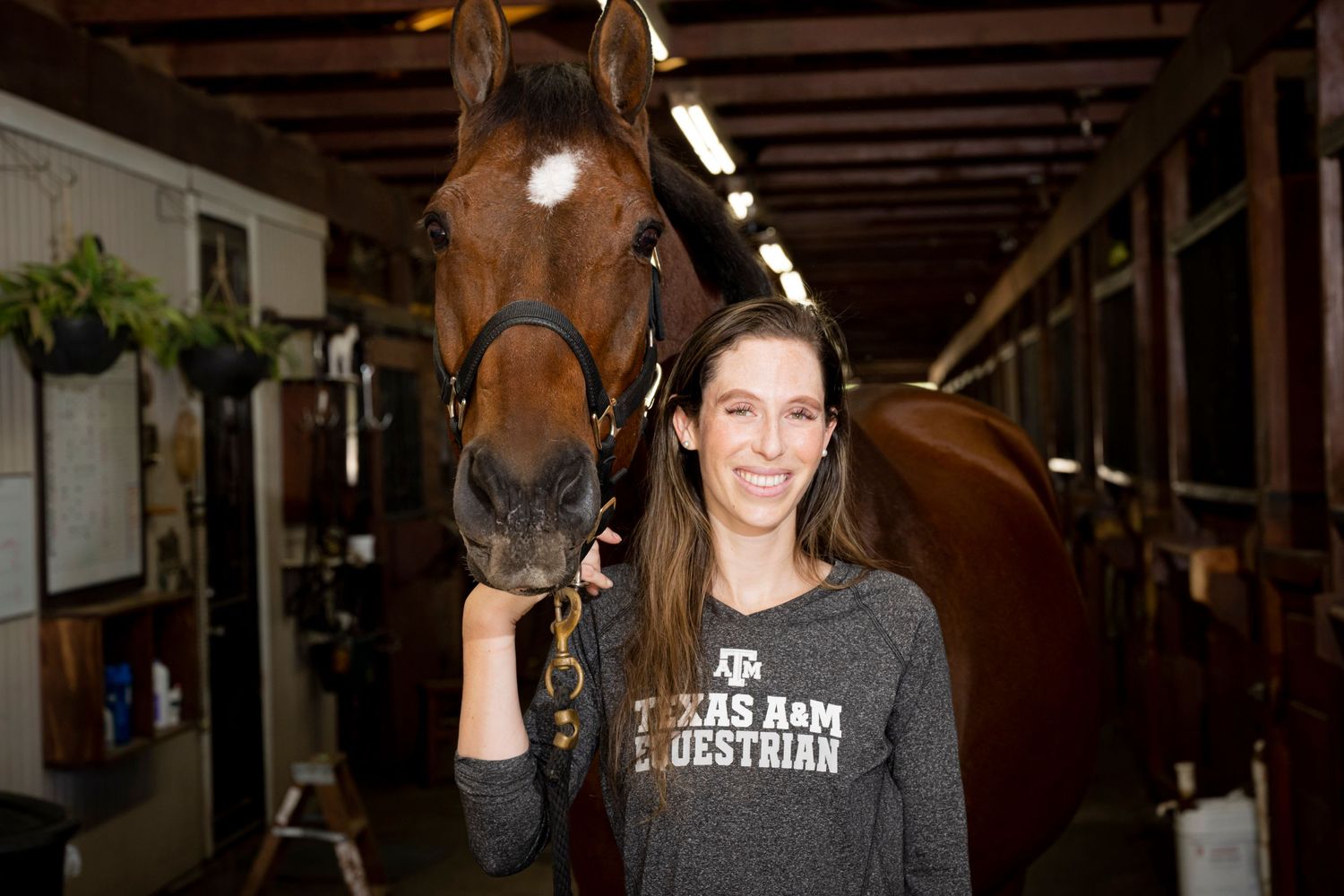 Equestrian with brown horse inside stable wearing Texas A&M shirt. Scotch Plains Photographer, portrait photography.