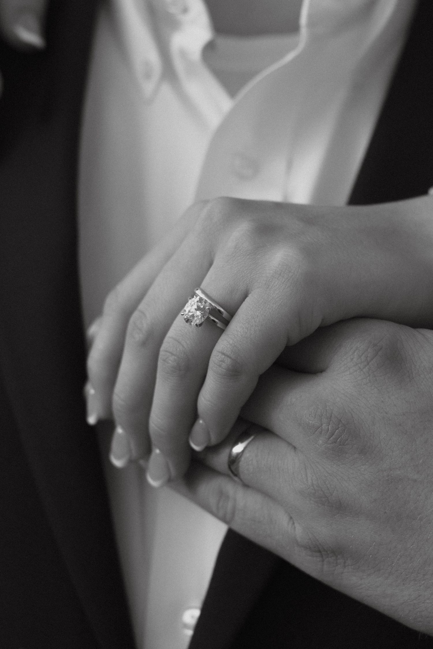 Black and white photo showing hands with wedding rings, with one hand wearing an engagement ring. engagement photoshoot Denver Colorado