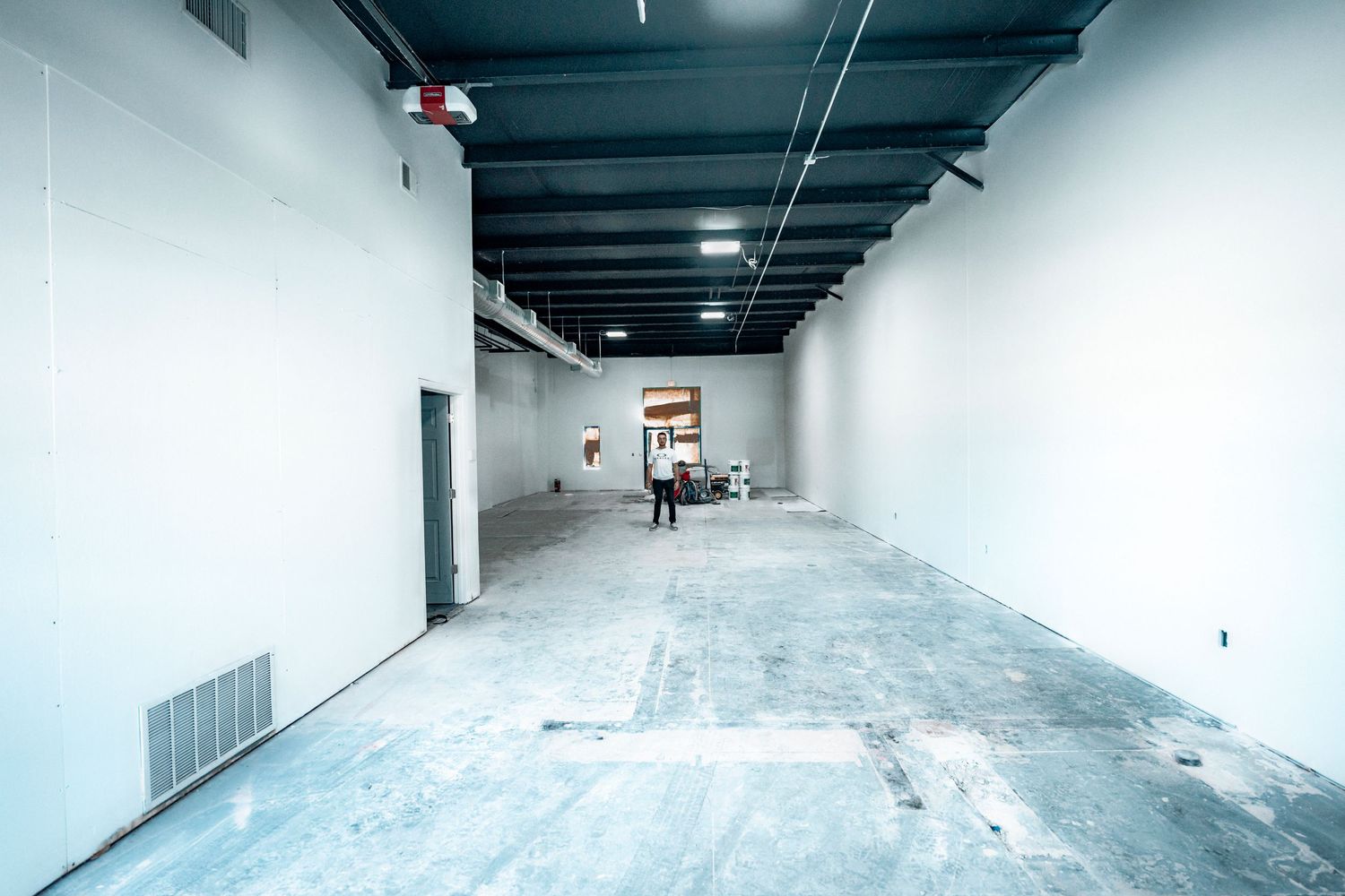Long empty hallway with white walls and concrete floor under construction.