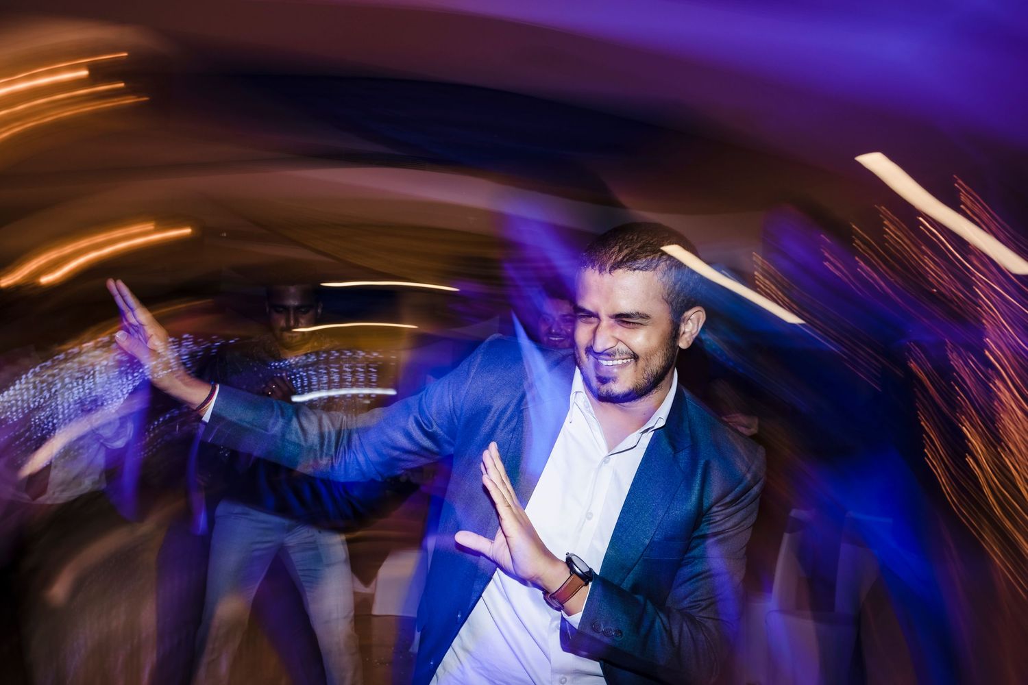 Person in blue blazer dancing with dramatic motion blur and colorful lighting effects.