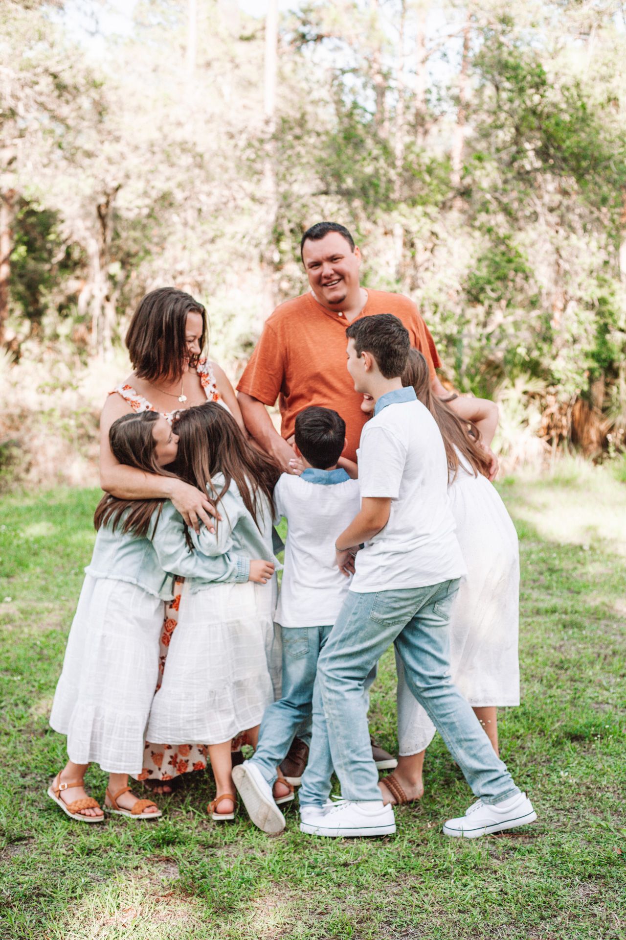 Family group sitting together on grass in coordinated white and denim outfits.