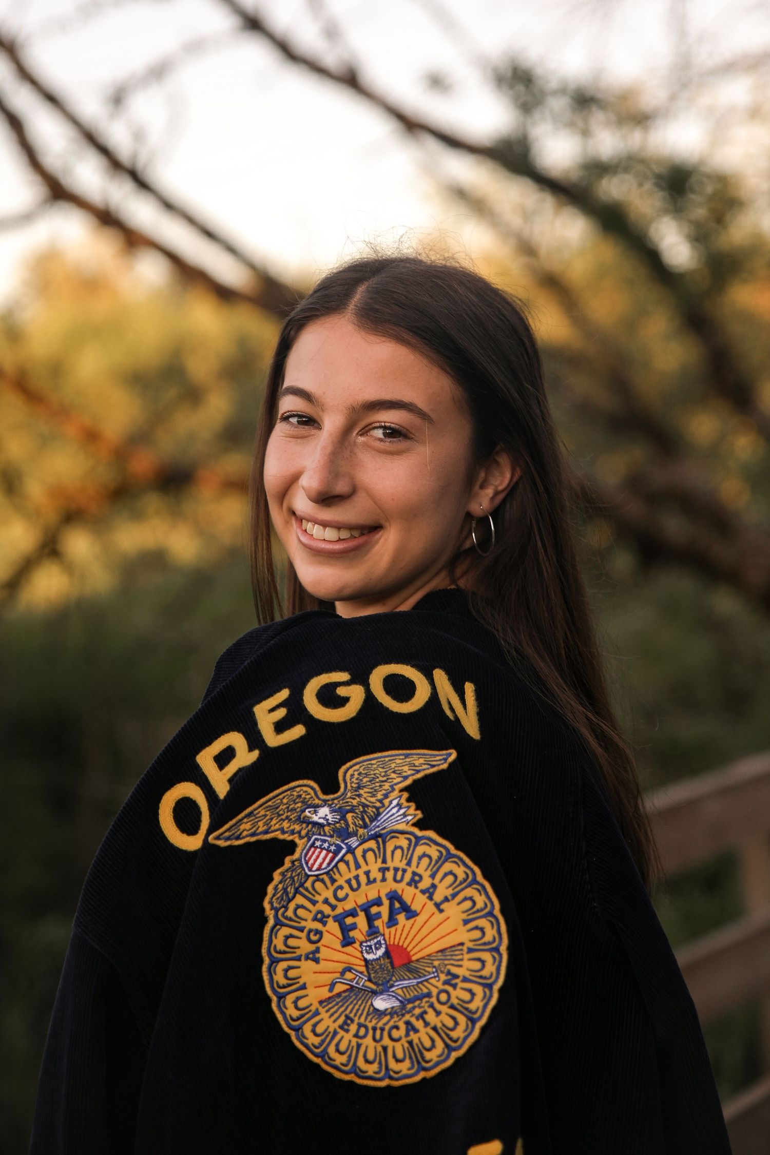 Person wearing Oregon FFA sweatshirt smiles during golden hour outdoors.