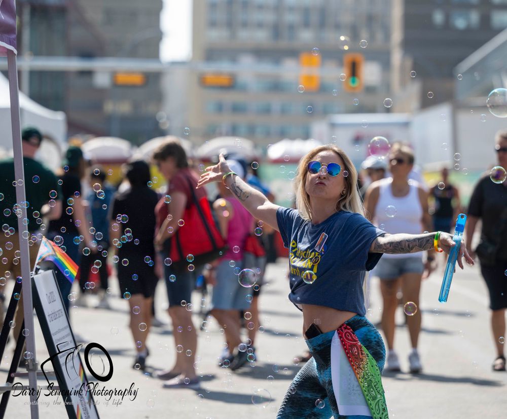 People enjoying a sunny day at the beach boardwalk with skateboards and wheelchairs in an urban setting.