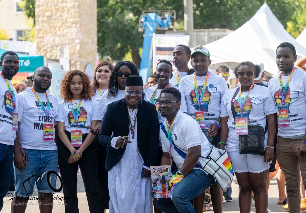 Large group of people wearing matching white t-shirts gather outdoors for a community event.
