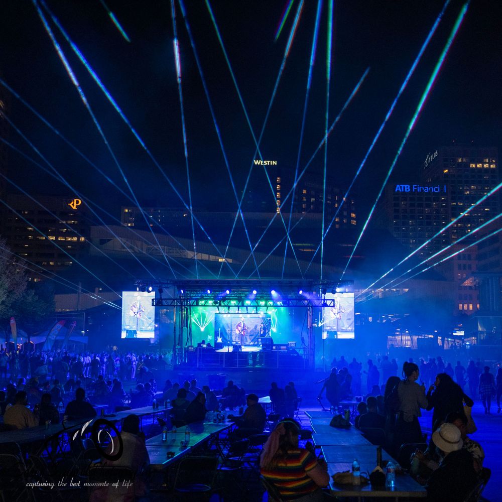Concert arena illuminated with bright blue laser beams and spotlights creating a dramatic nighttime atmosphere.