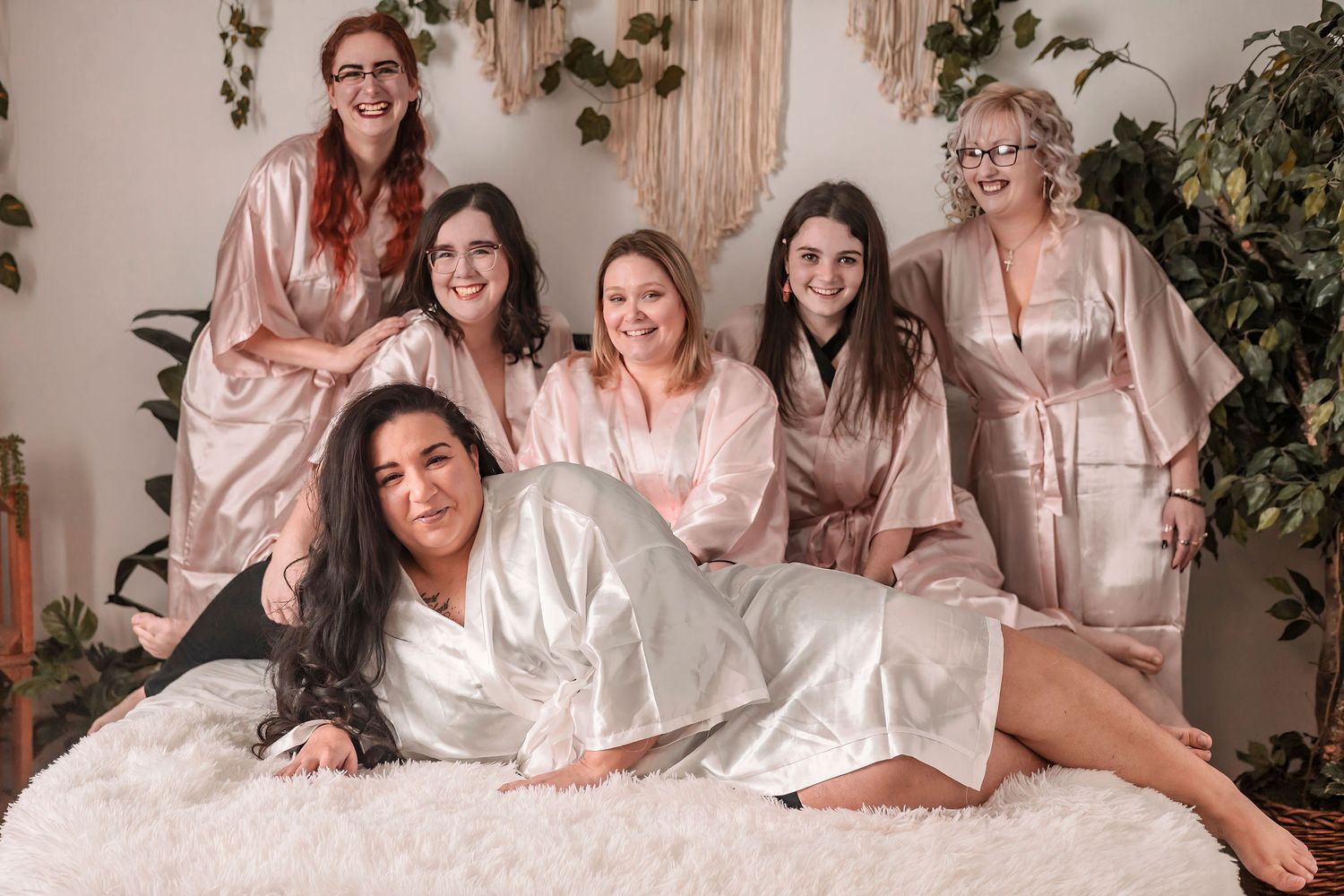 Group photo of friends in matching robes posing together at indoor celebration.