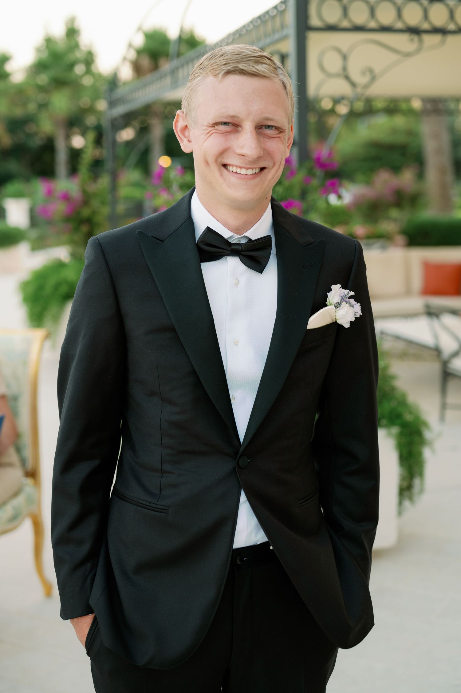 Classic black tuxedo with bow tie worn at outdoor wedding venue.