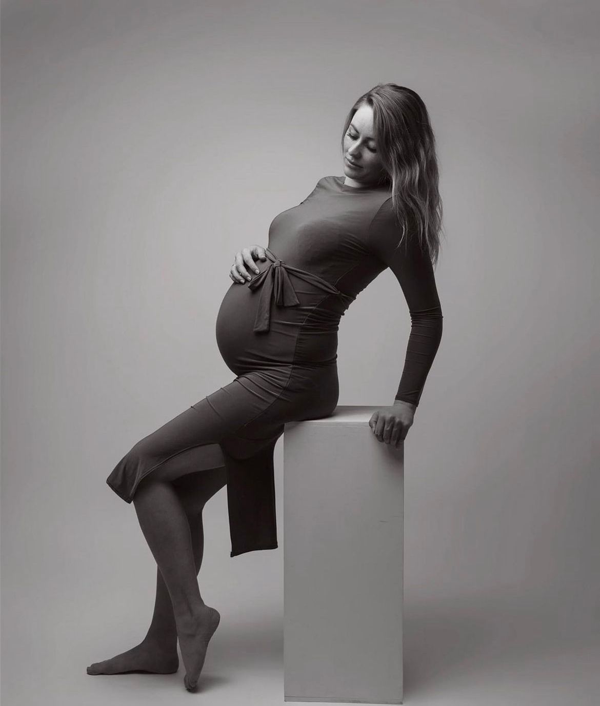 Kunstneriske graviditetsfotos, der viser en gravid figur i elegante positurer mod en minimalistisk baggrund.