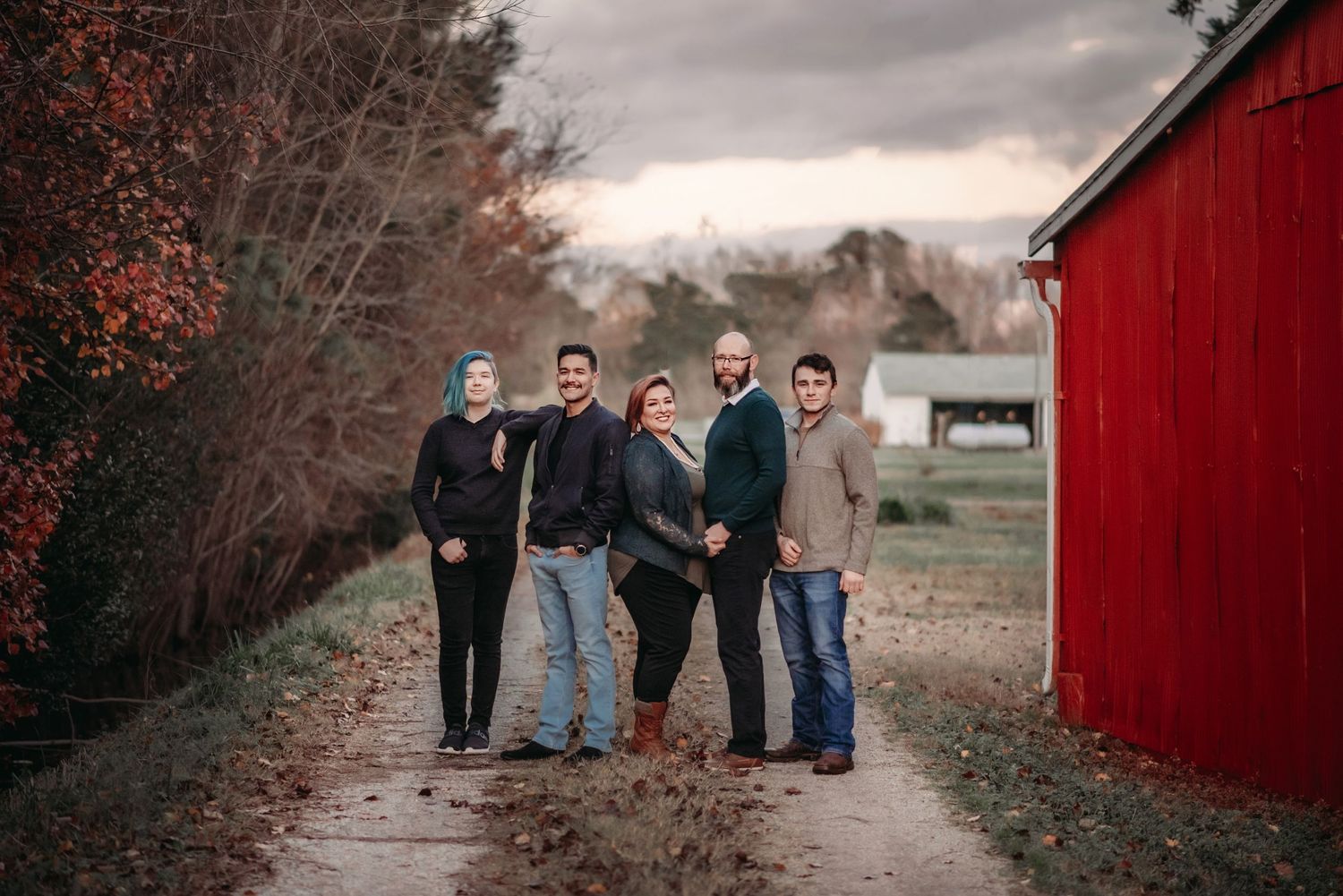 a photo of a family standing in a driveway by a red barn