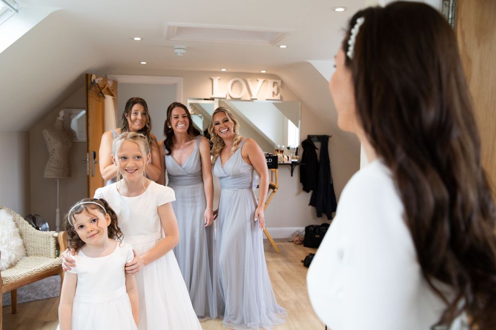 Wedding party gathering in a bright attic space with bridesmaids wearing light blue dresses.