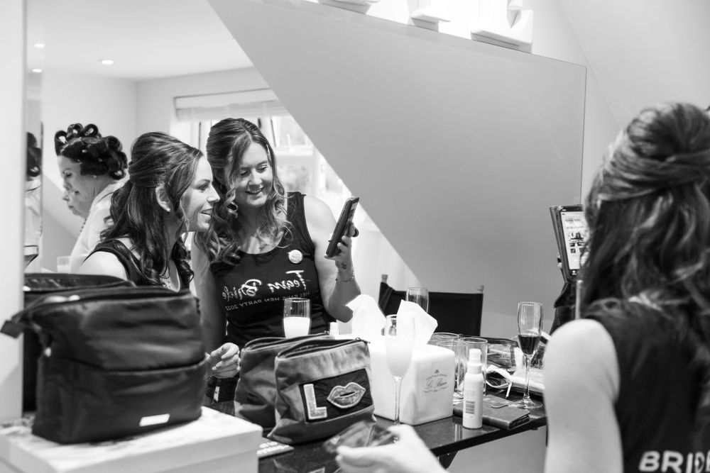 Behind-the-scenes moment of wedding preparation in bright makeup room.