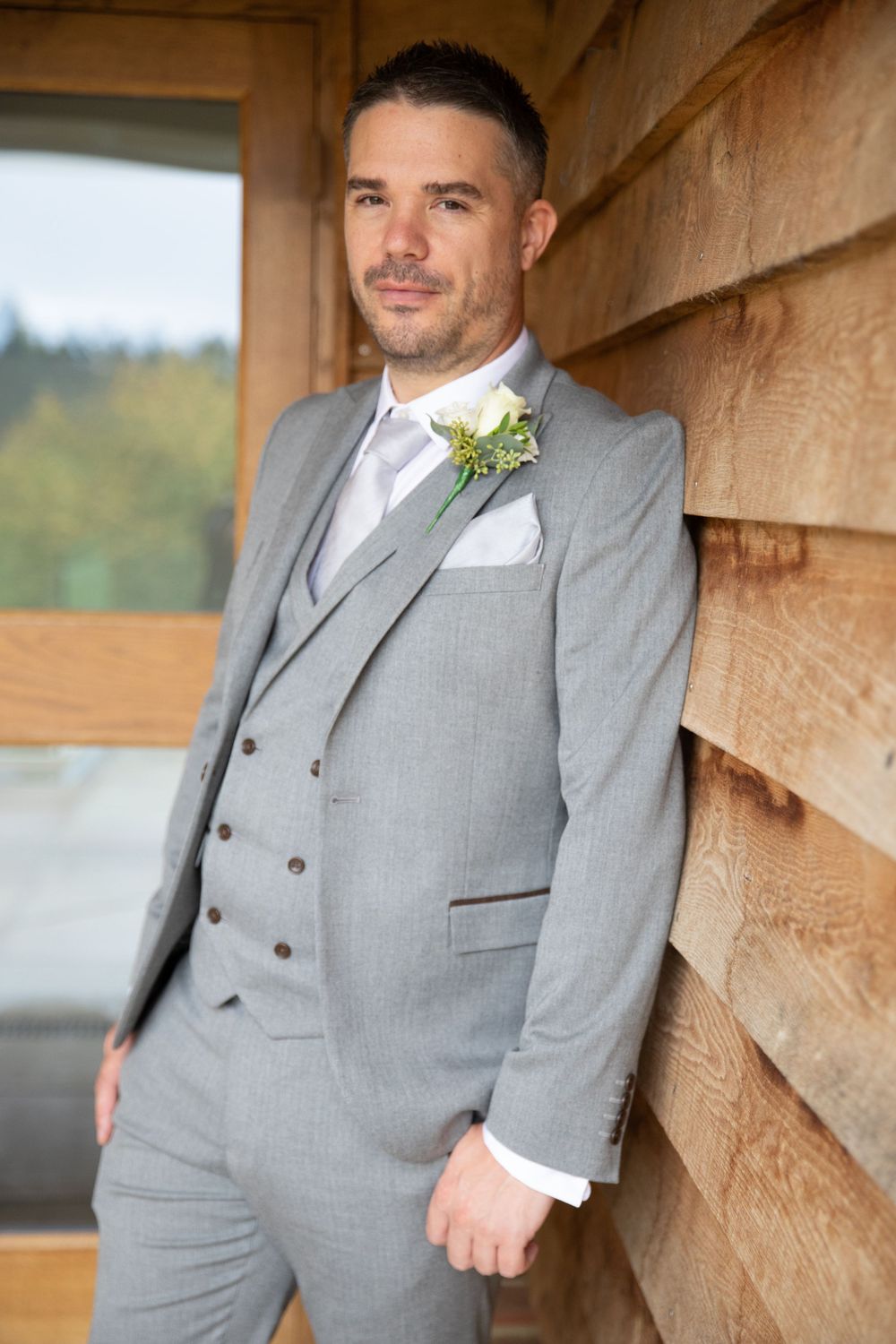 Formal portrait of groomsman in light grey three-piece suit with boutonniere.