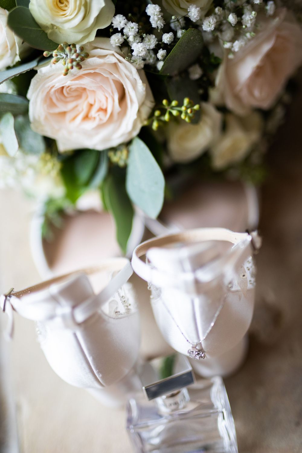 Delicate blush roses and white floral arrangements with crystal wedding shoes.