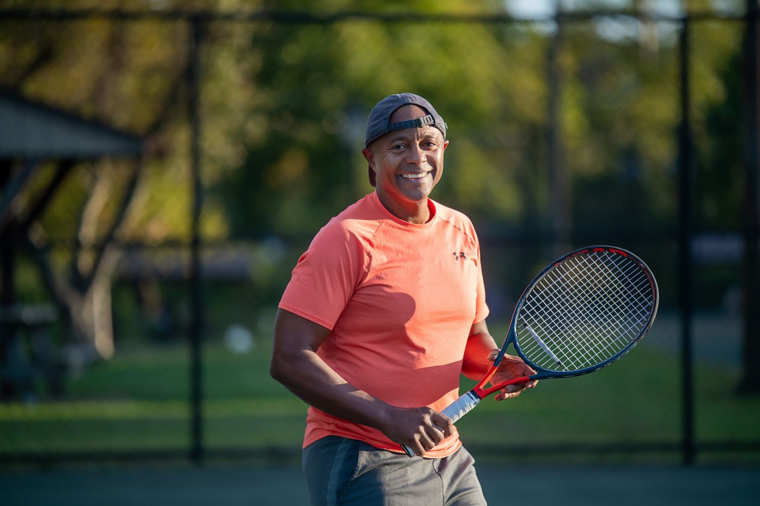 A tennis player poses with racquet on court during golden hour.