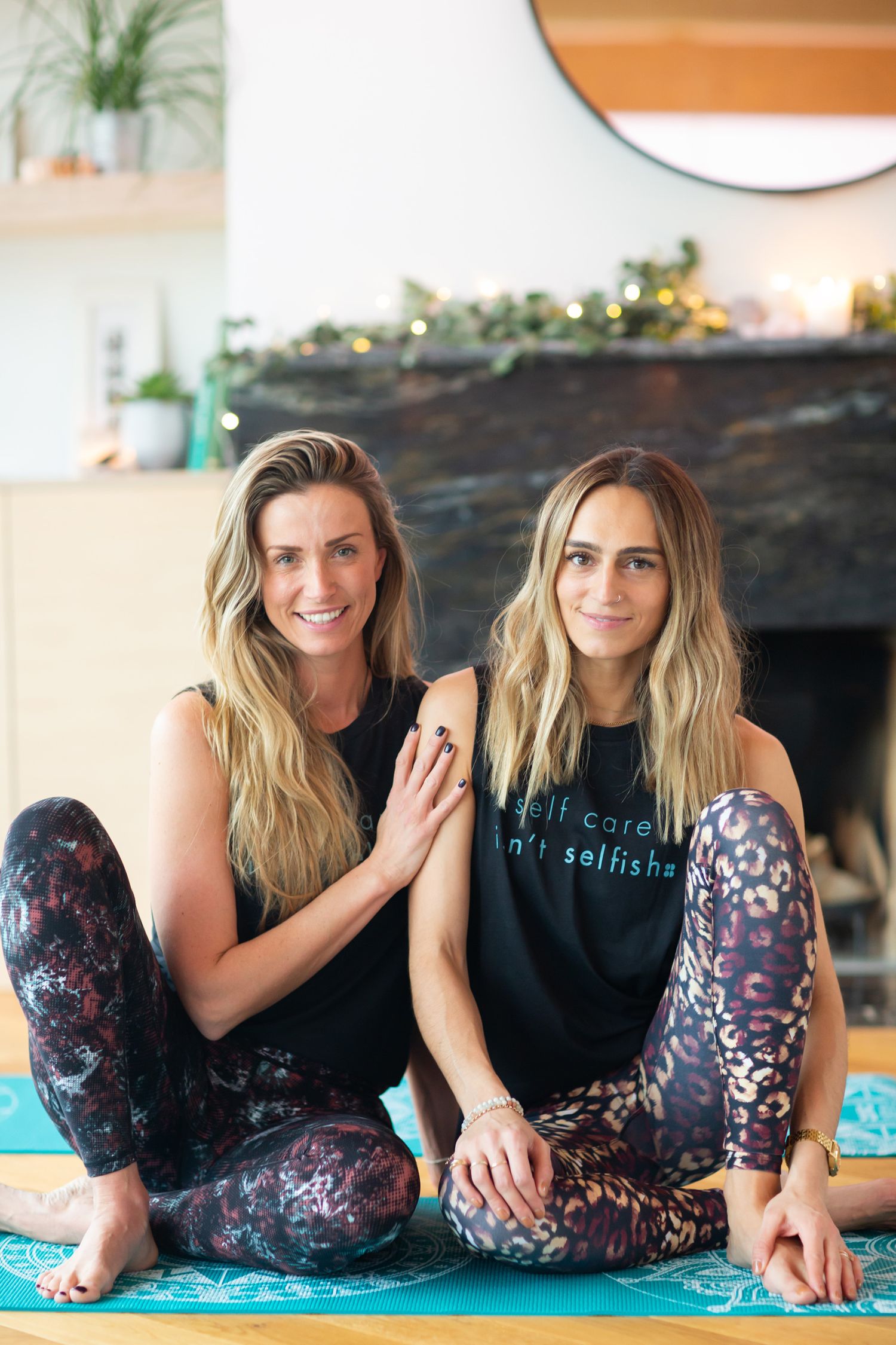 Two people in athletic wear sitting on yoga mats in front of a fireplace during business branding photoshoot.