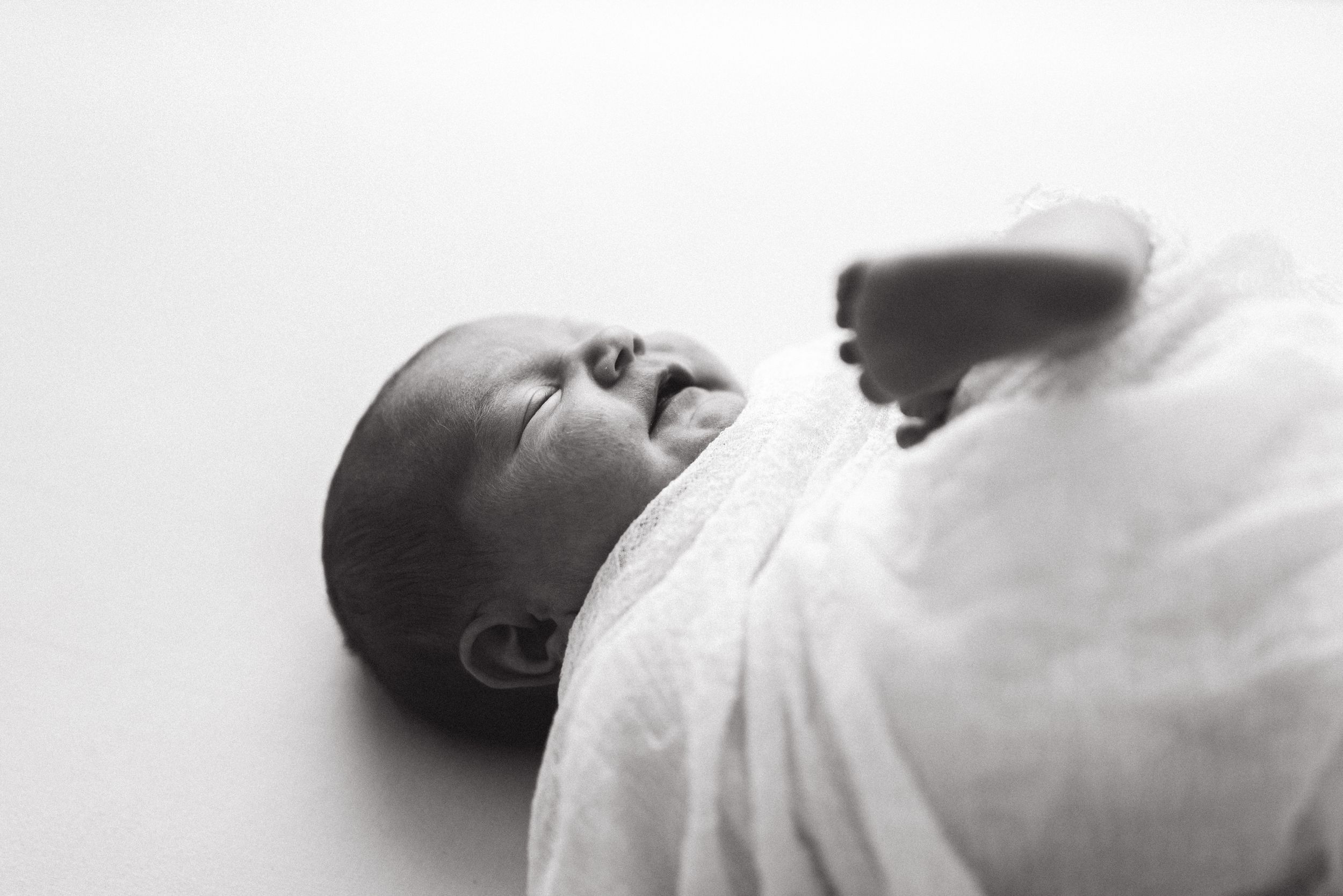 Mustavalkoinen newborn-kuva, josta näkyy vauvan varpaat ja sivuprofiili.