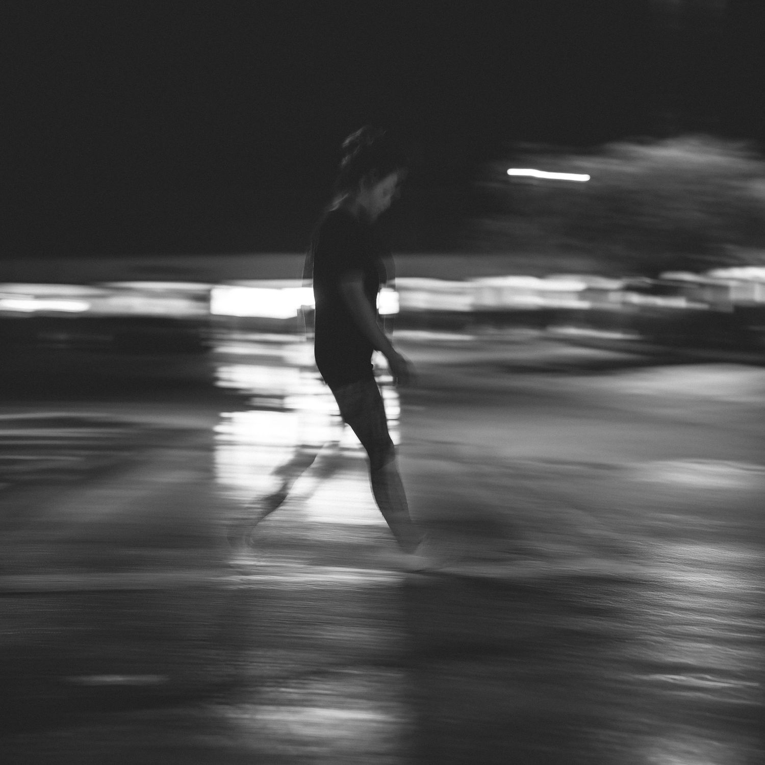 Blurred black and white motion shot of a silhouette running at night.