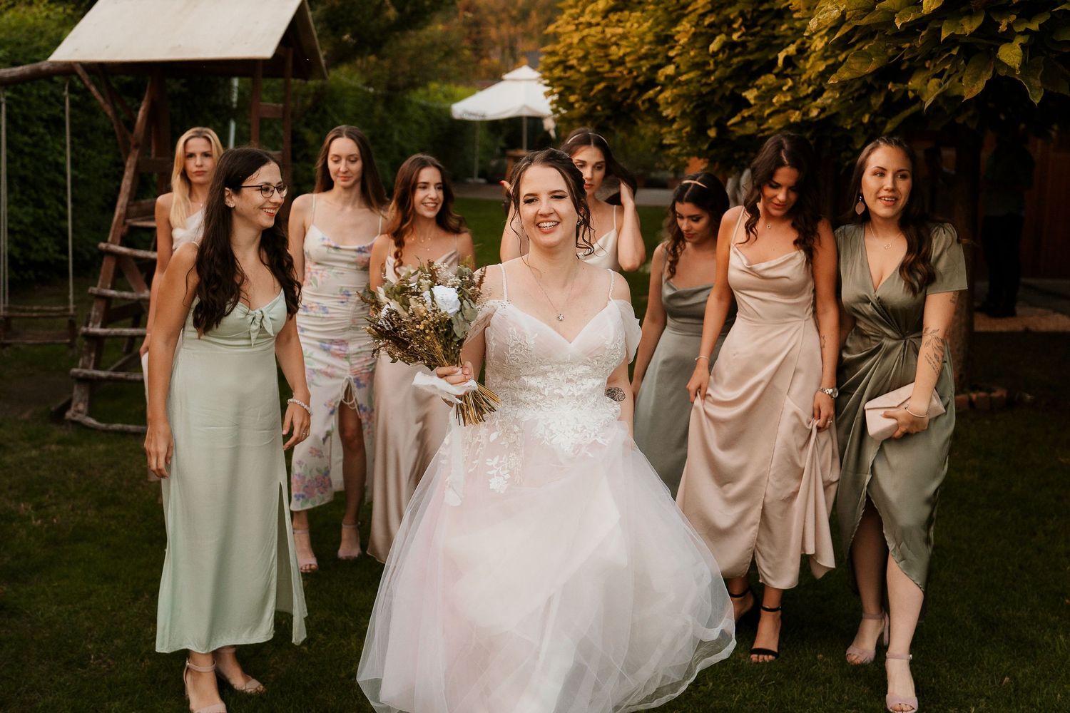Wedding party walking together outdoors with autumn foliage in background.