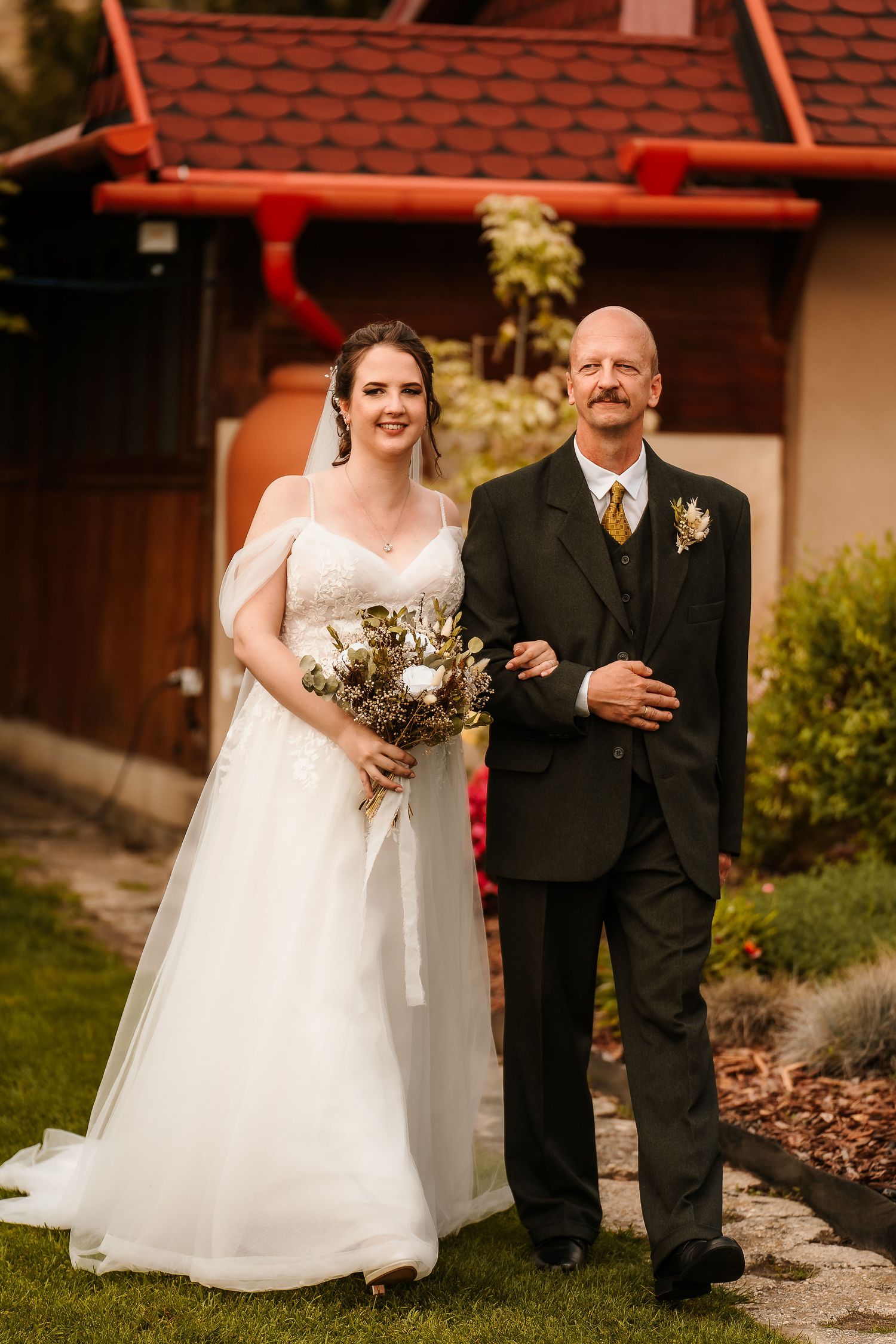 Traditional wedding moment with formal attire and neutral floral bouquet in garden setting.