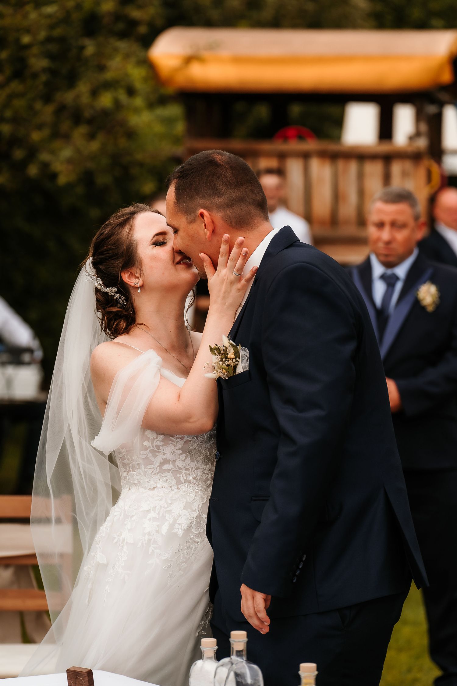 Emotional wedding kiss captured during an outdoor garden ceremony with guests looking on.
