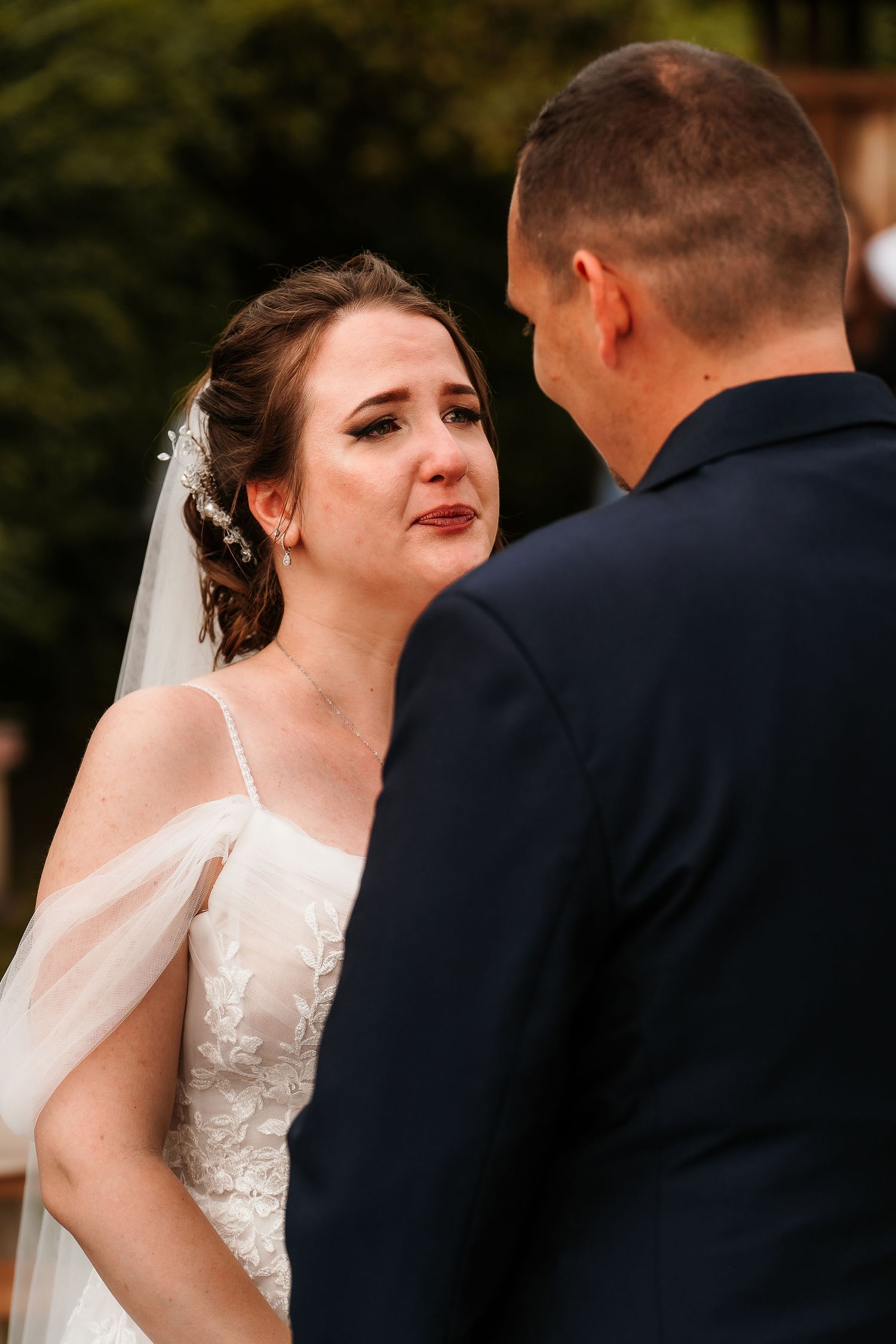 Emotional wedding ceremony moment captured during exchange of vows outdoors.