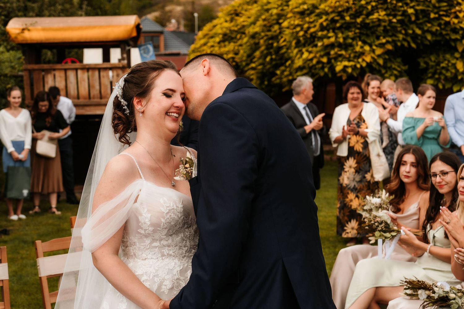 Joyful wedding ceremony moment with guests looking on in garden setting.