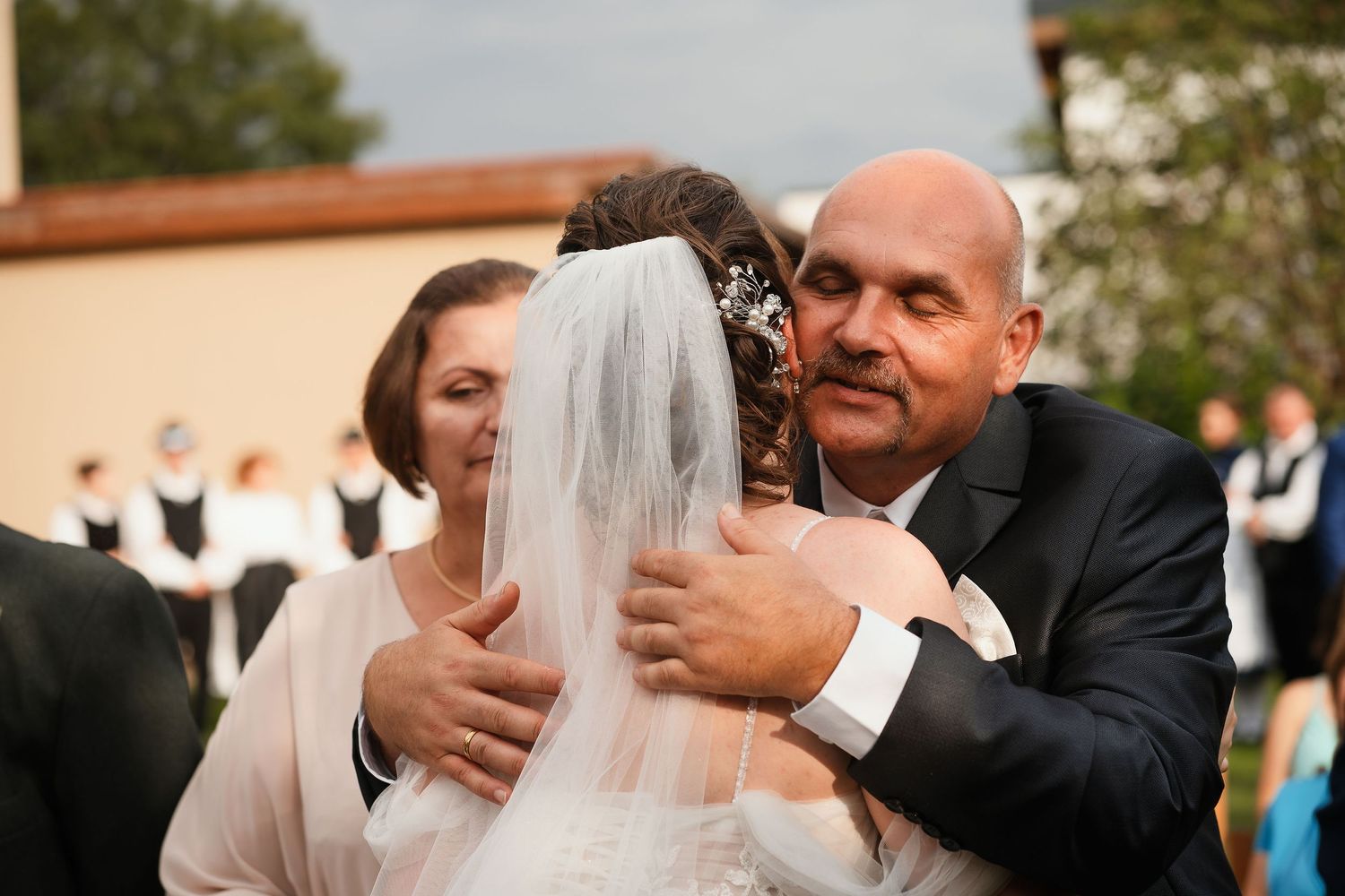 An emotional embrace during an outdoor wedding ceremony on a sunny afternoon.