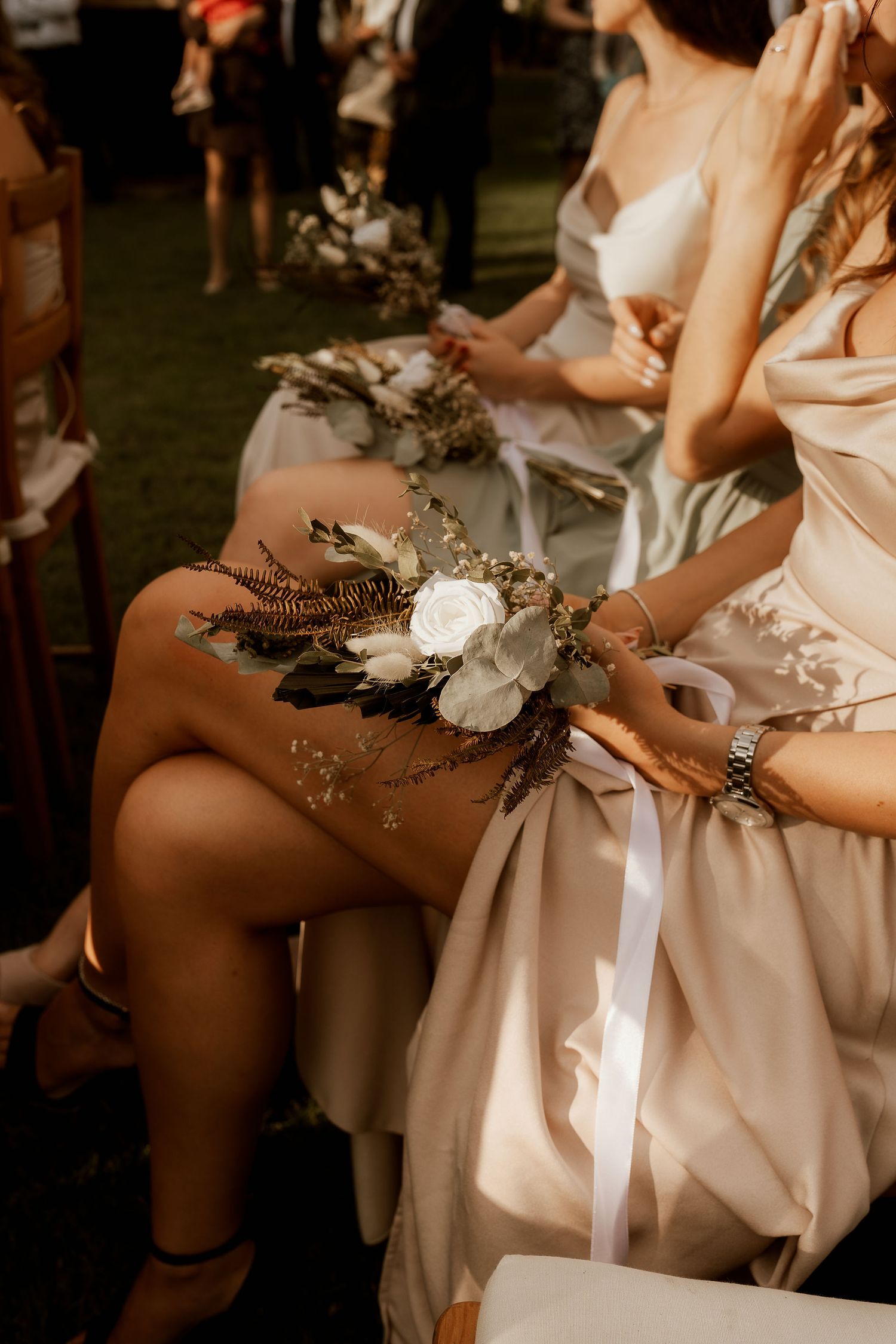 A delicate floral corsage with white flowers and greenery rests on a satin dress.