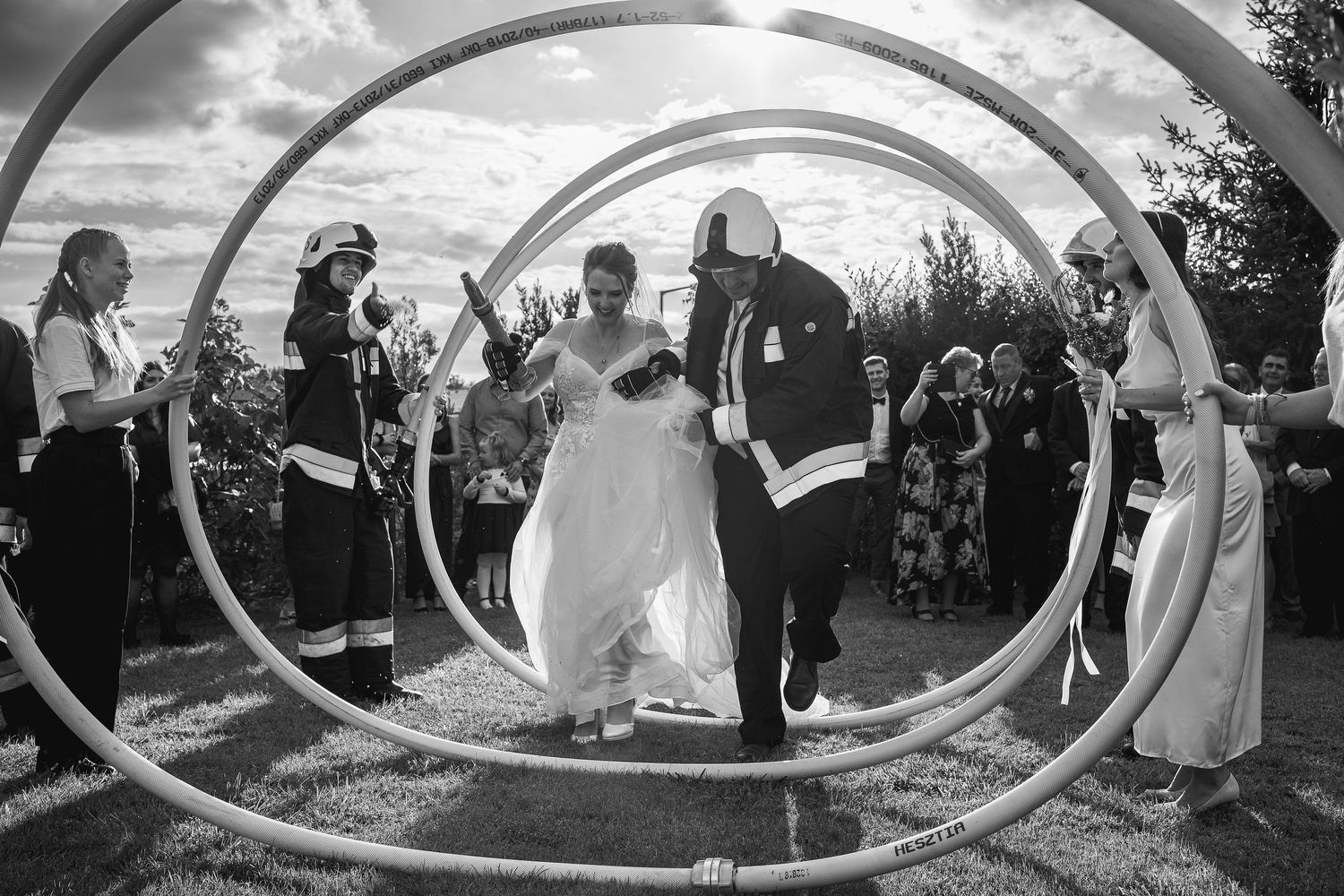 Wedding party walks through decorative circular arches during outdoor ceremony.