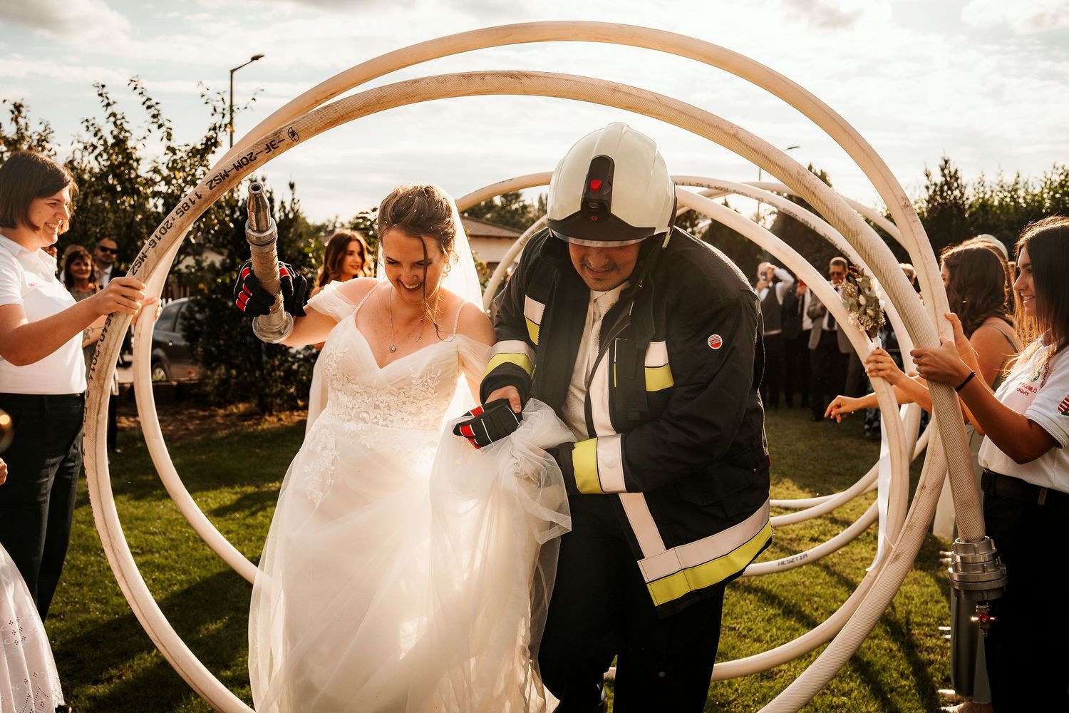 Couple walks through curved archways at outdoor wedding celebration.