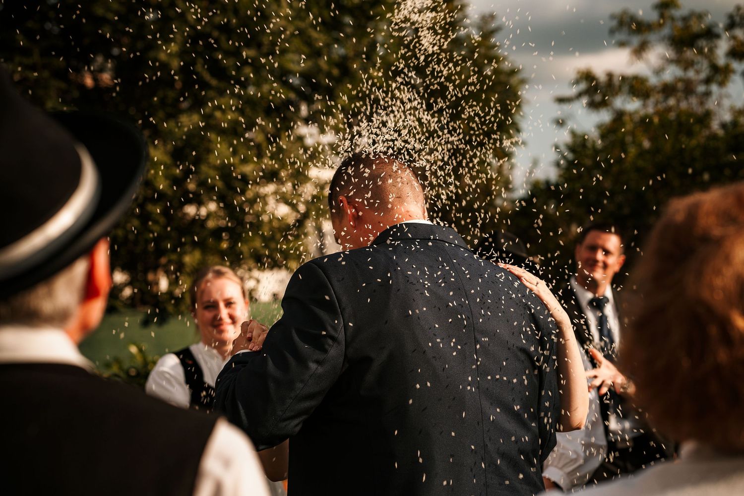 Water sprays over wedding celebration creating sparkling effect in sunlight.