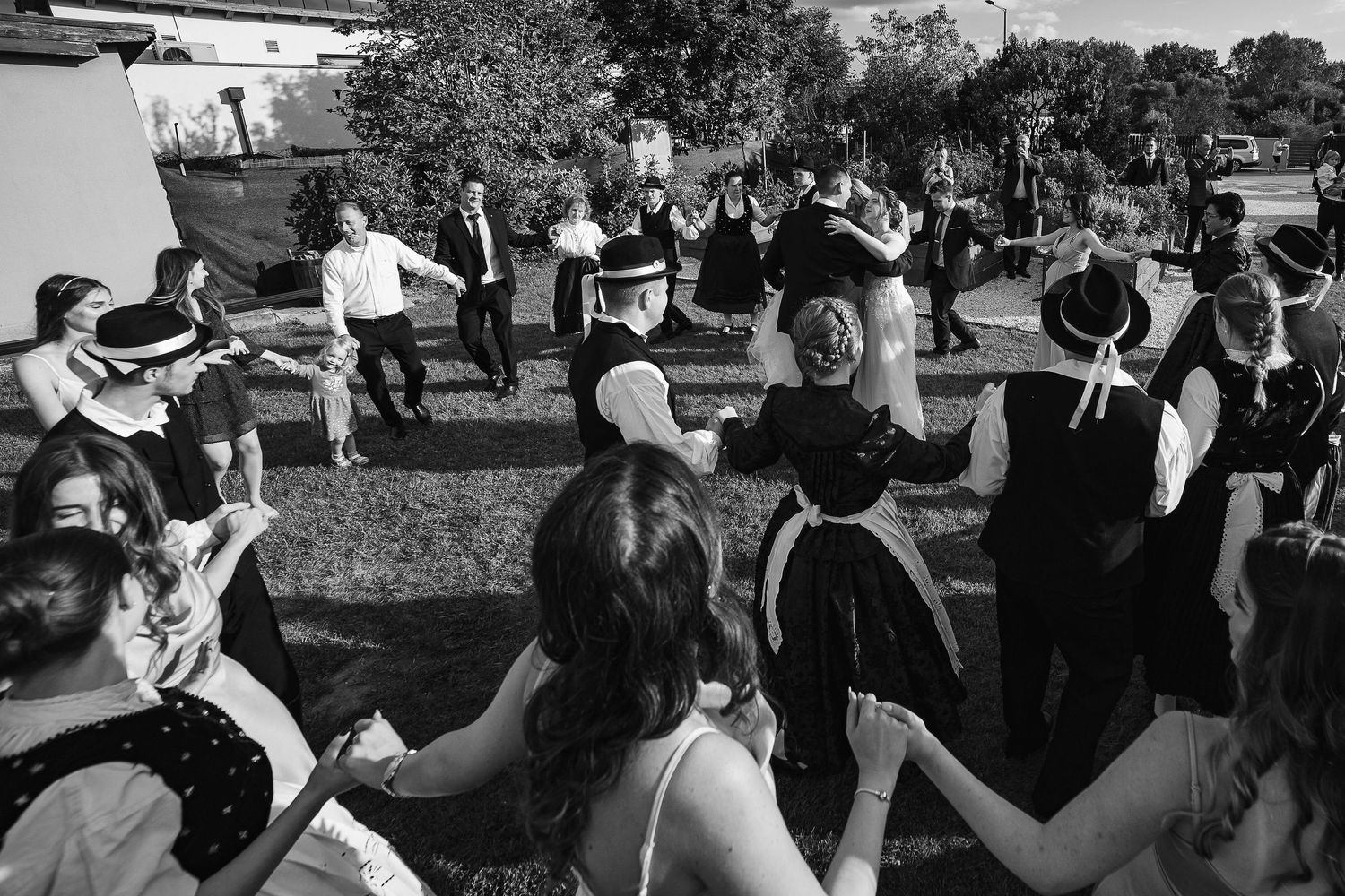 Traditional dance circle forms during outdoor wedding reception.