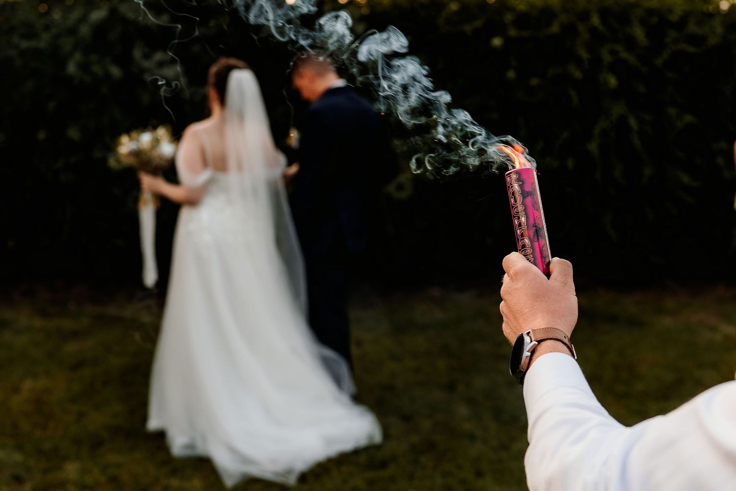 A smoke bomb creates dramatic effect as newlyweds pose in the distance.