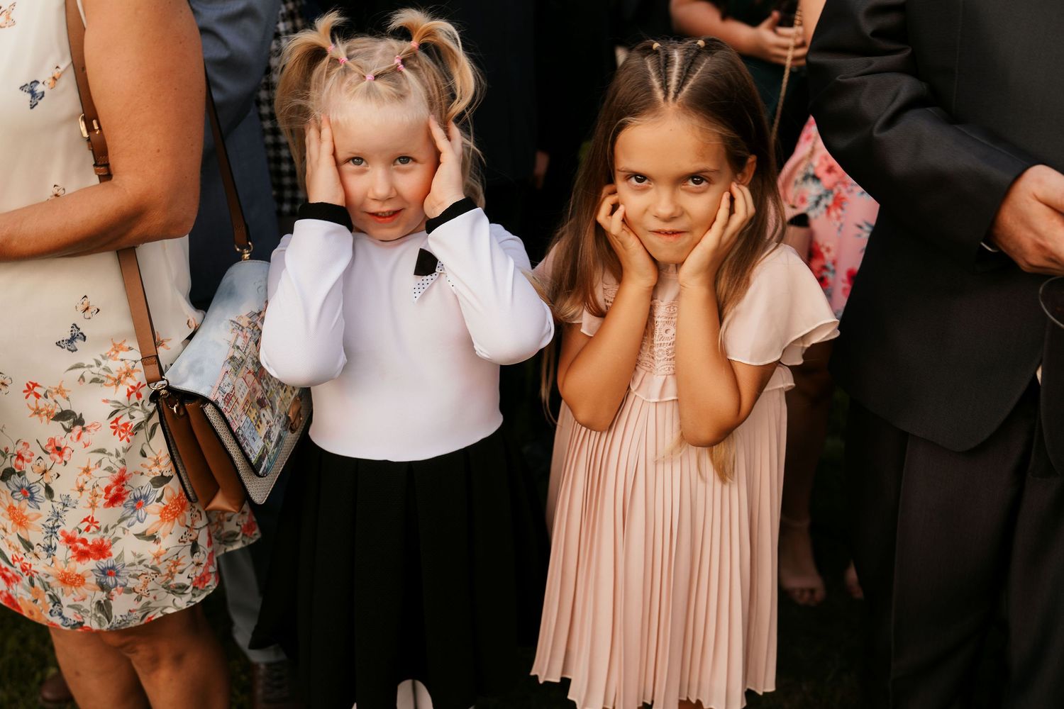 Two young children in formal attire cover their ears during a wedding ceremony.