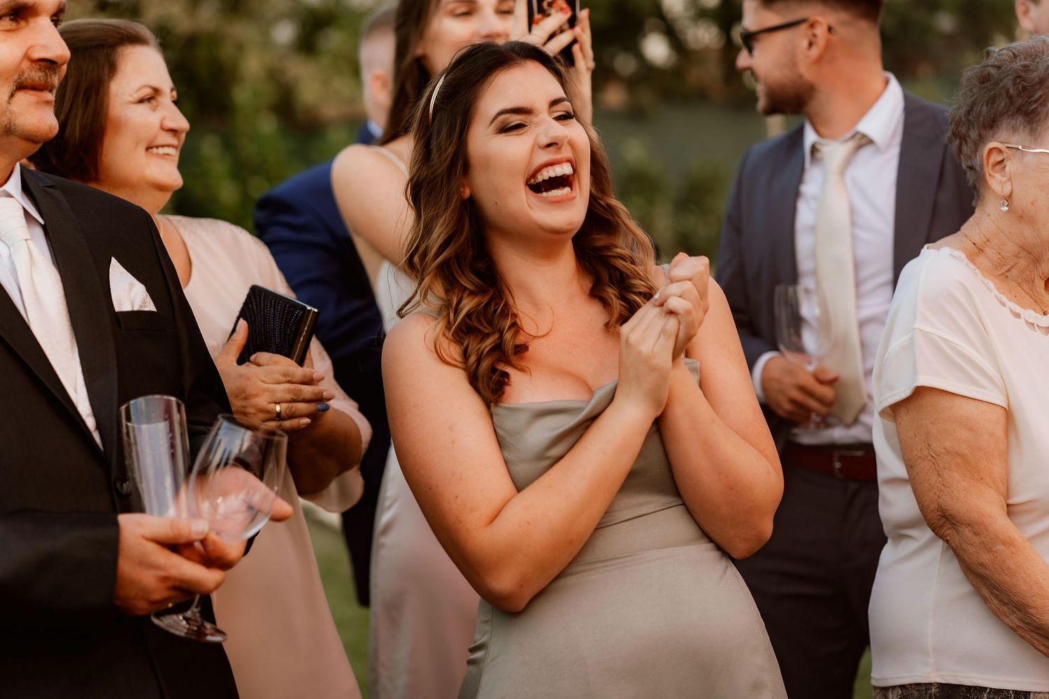 Wedding guests laugh and celebrate during an outdoor cocktail reception.