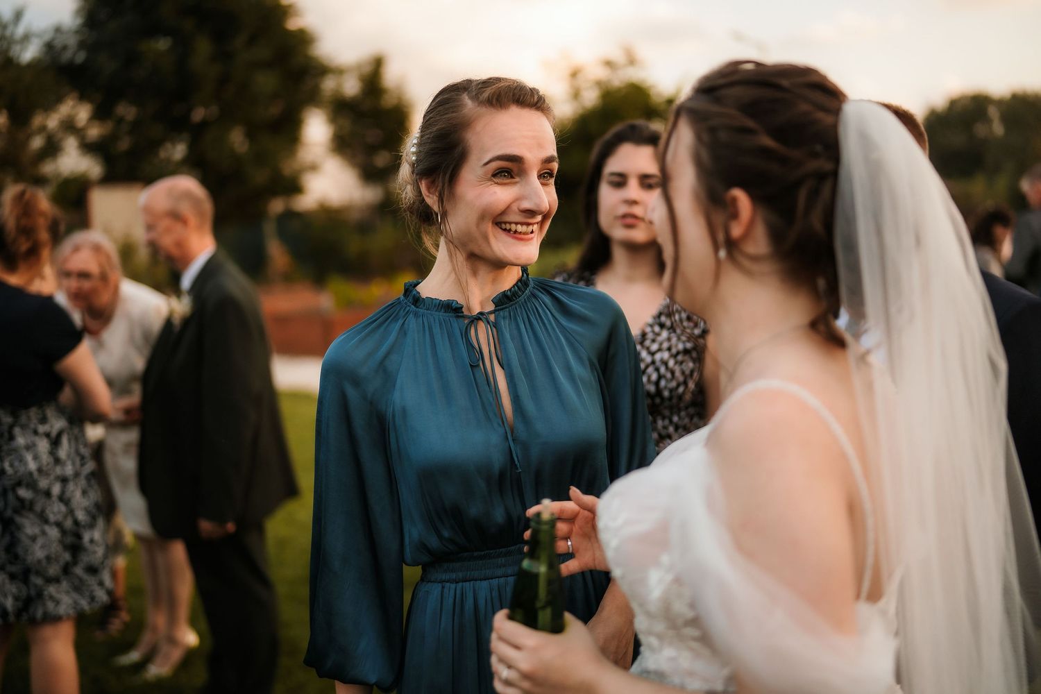 Festive outdoor wedding reception with guests mingling at sunset.