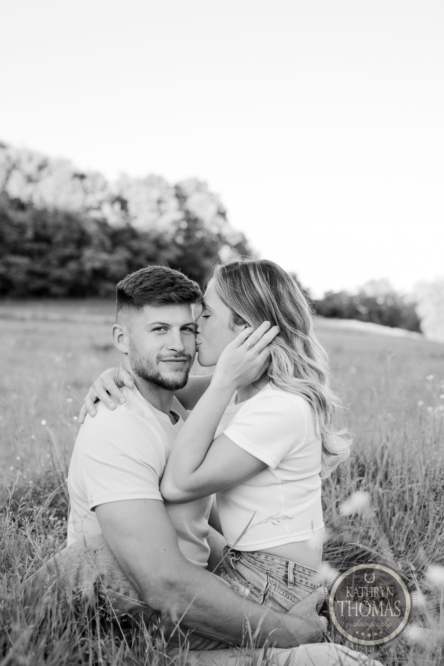 Black and white portrait of couple sharing an intimate moment in a meadow.